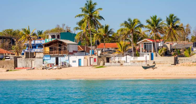 Pueblo costero colorido con palmeras y agua turquesa tranquila bajo cielos despejados