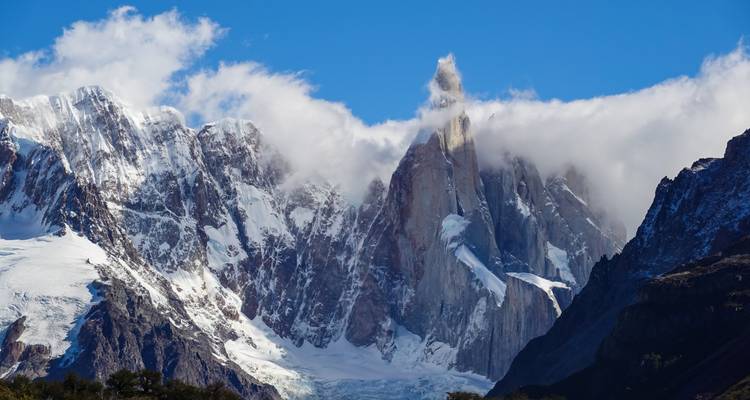 Dramatische Granitspitze des Cerro Torre durchstößt Wolkenballen über Gletschern und schroffen patagonischen Gipfeln.