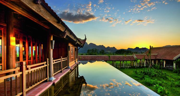 Reflectie van een huis en berg in een poel tijdens zonsopgang.