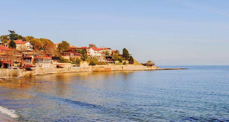 Küstenblick auf ein Dorf mit traditionellen Häuschen und ruhiger See.
