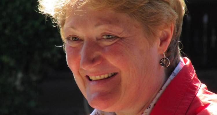 Nahaufnahme einer lächelnden Frau draußen bei Tageslicht.