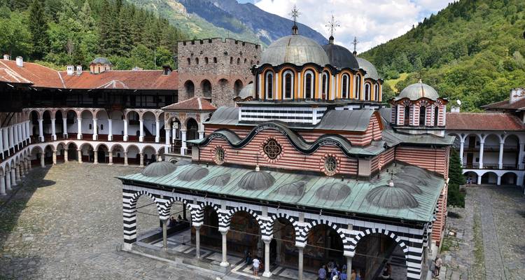 Ein Klosterkomplex, umgeben von Bergen und Wald.