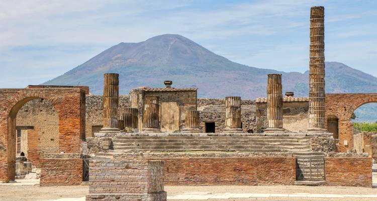 Antiguas columnas de ladrillo y ruinas de Pompeya se alzan ante el pico cónico del Monte Vesubio