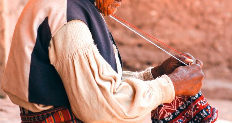 Alte Frau in traditioneller Kleidung beim Weben.