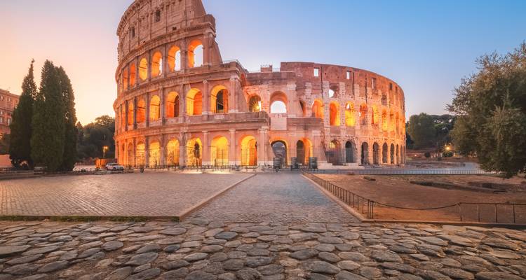 Colisée emblématique illuminé de lumières chaudes au crépuscule sous un ciel pastel.