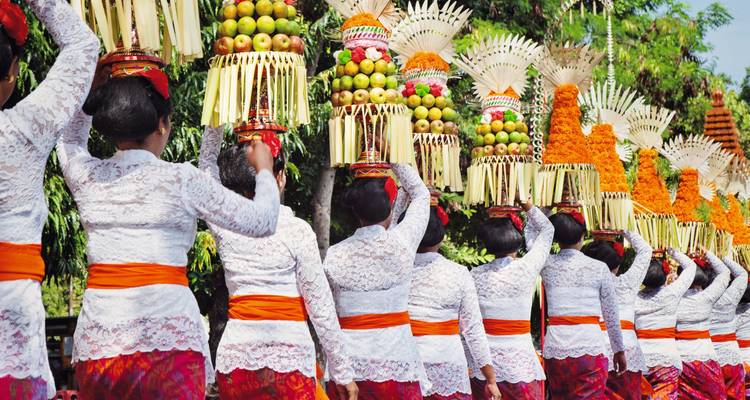 Vrouwen die offers dragen op hun hoofd in traditionele kledij.
