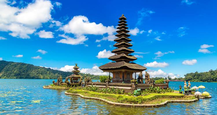 Ikonischer Seetempel Pura Ulun Danu Bratan spiegelt sich in ruhigen Gewässern unter hellen Wolken wider.