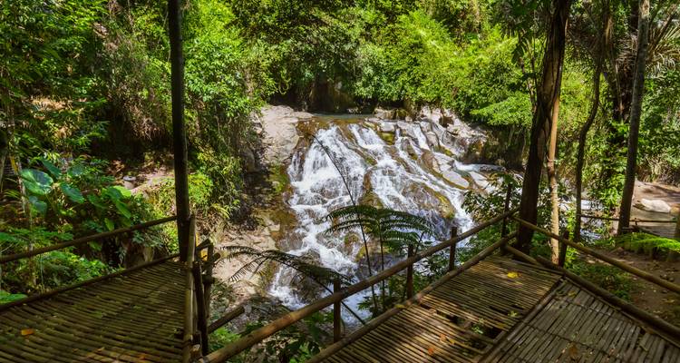 Hölzerne Aussichtsplattformen überblicken eine kleine Kaskade, die durch dichten tropischen Wald in Munduk stürzt.