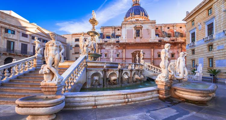 Marmorstatuen und kaskadierende Becken des Pretoria-Brunnens vor der historischen Palastkulisse in Palermo.