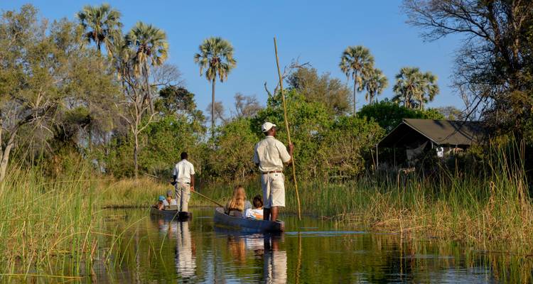 Mensen in traditionele boten die door een waterweg peddelen.