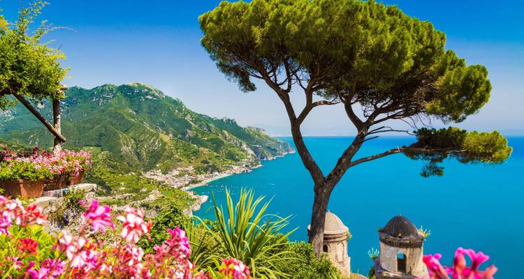 Vue panoramique de la côte amalfitaine avec des fleurs éclatantes et des montagnes.