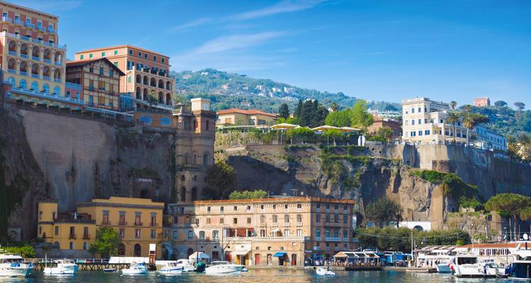 Bunte Gebäude an der Meeresfront und Yachten, die im Hafen unter Sorrentos dramatischen Klippen festgemacht sind.