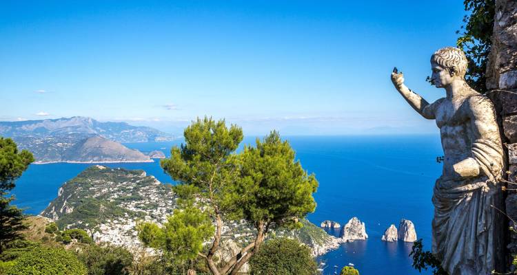 Une vue panoramique depuis une colline surplombant le littoral avec une statue au premier plan.