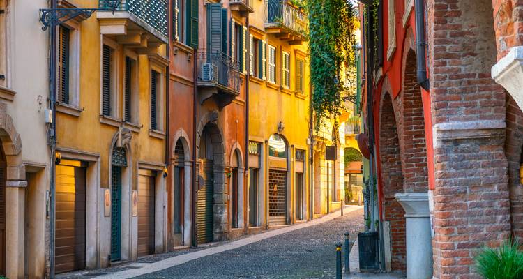 Ruhige, warm beleuchtete schmale Straße, gesäumt von bunten historischen Gebäuden in Verona.