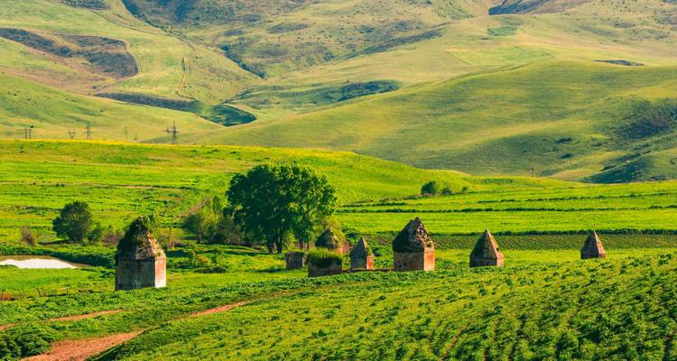 Rural landscape with ancient stone structures surrounded by green hills.