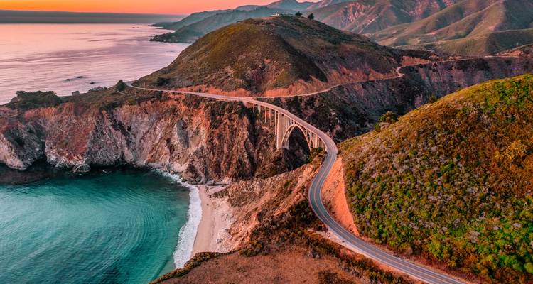 Vista aérea al atardecer del Puente Bixby Creek serpenteando a lo largo de la escarpada costa de Big Sur.