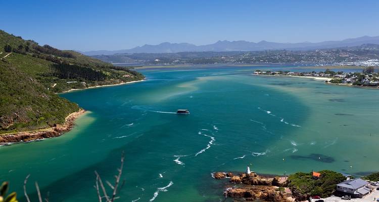 Scenic view of a lagoon with a boat and coastal settlement.