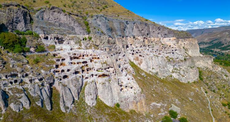 Ausgedehnte Klippenstadt Vardzia in Höhlen, in Kalksteinwände gemeißelt unter blauem Himmel.