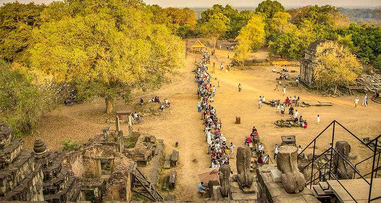 Lange rij mensen bij een tempelcomplex met uitgestrekt uitzicht.
