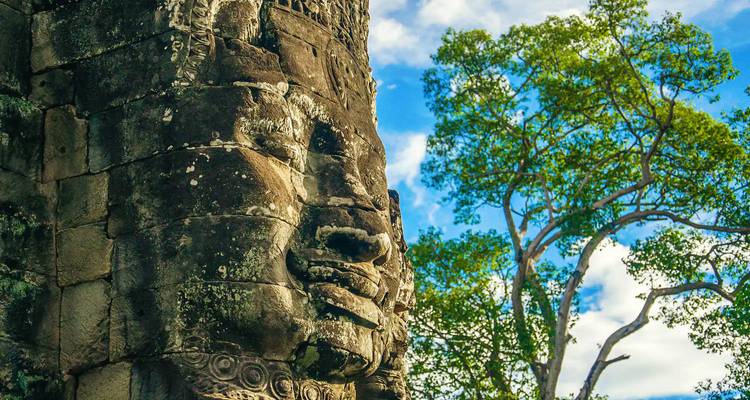 Close-up van een stenen gezicht bij de Bayon-tempel met blauwe lucht.