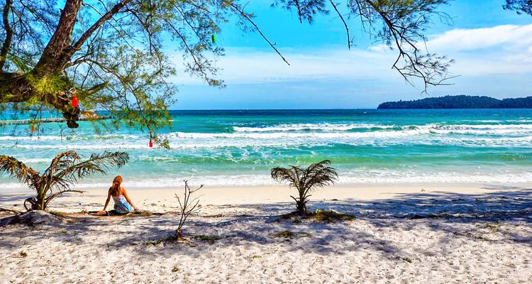 Een persoon die op een ongerept strand zit met tropische wateren.