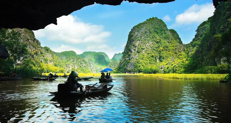 Een serene riviercruisescène met kalksteenformaties en toeristen op boten.