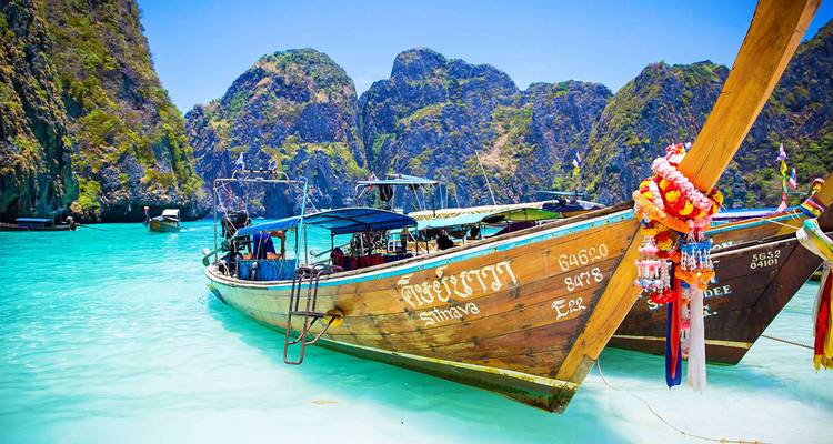 Bateaux à longue queue sur une eau turquoise claire près des falaises.