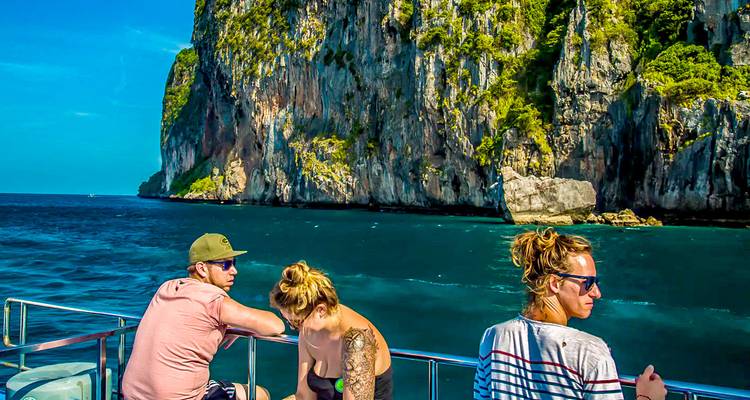 Des gens sur un bateau près d'une grande formation rocheuse.