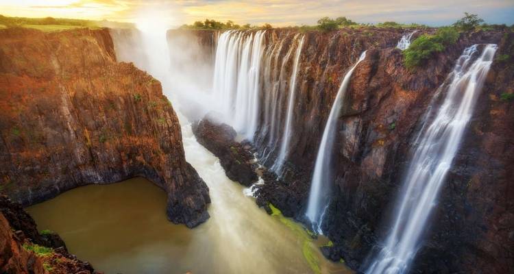 Schilderachtige waterval bij zonsondergang met weelderige omgeving.