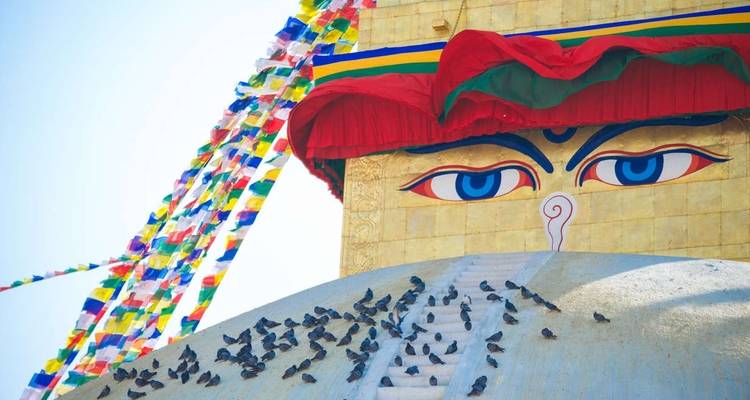 Large eyes on a stupa with prayer flags above in Kathmandu.