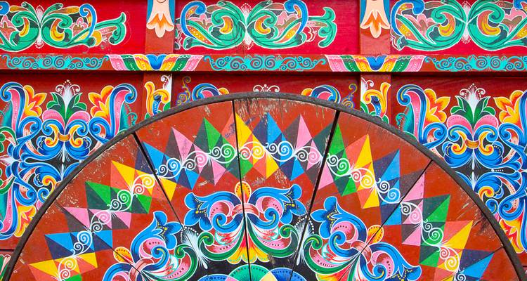 Gros plan vibrant d'une roue de chariot à boeufs traditionnellement peinte avec des motifs multicolores complexes.