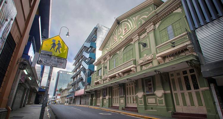 Calle tranquila del centro llena de edificios históricos ornamentados y modernos bajo un cielo nublado.
