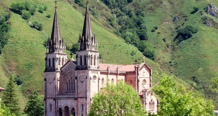 Una gran iglesia con torres gemelas en un exuberante paisaje montañoso.