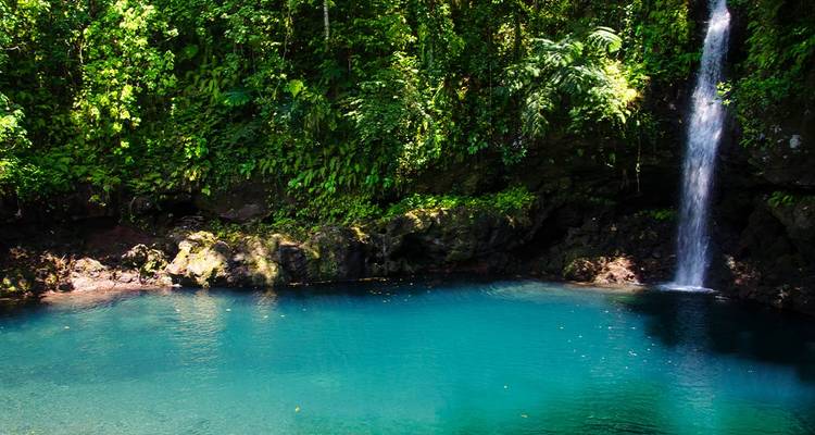 Tall waterfall cascading into a tranquil blue pool.
