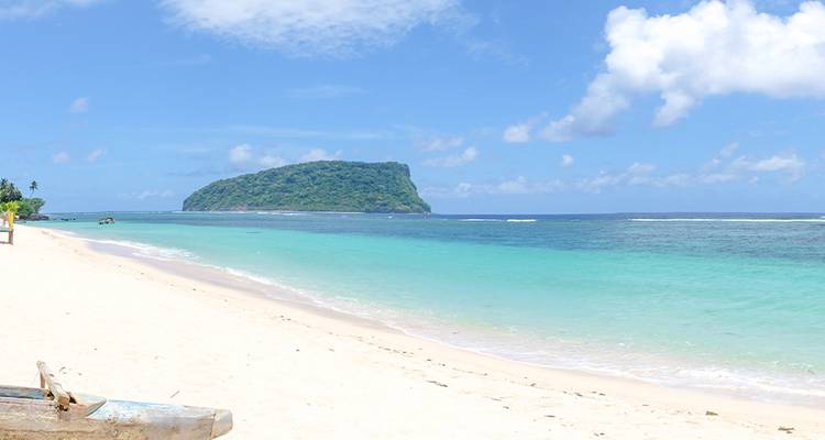 Pristine beach with turquoise water and a distant island.