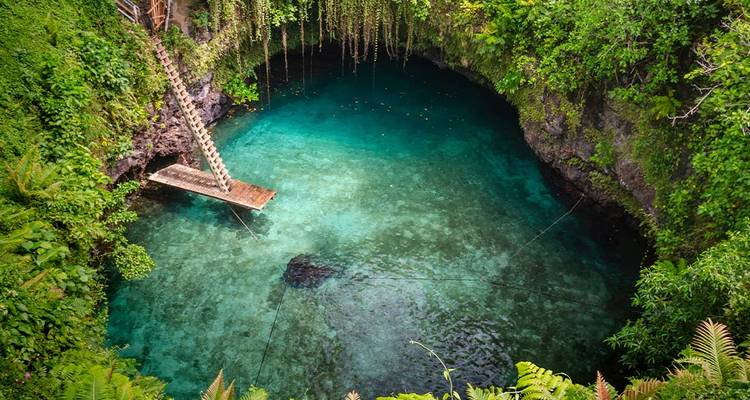 Crystalline water in a sinkhole with lush vegetation around.