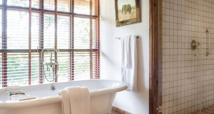 Luxuriöses Badezimmer mit freistehender Badewanne und großem Fenster.