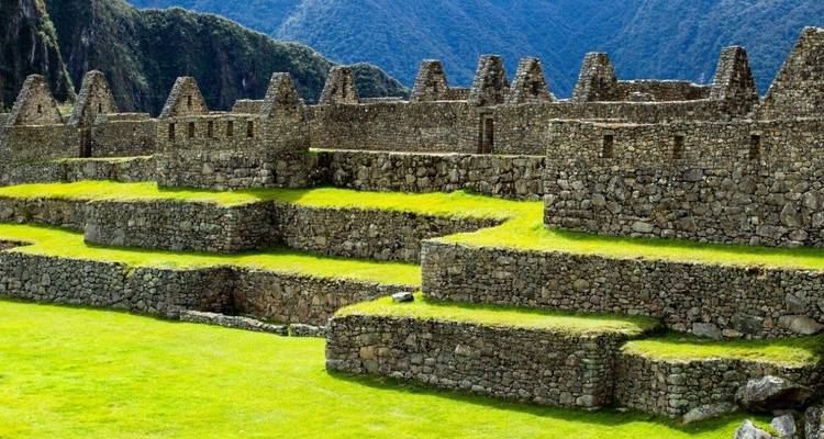 Stenen terrassen met ruïnes en bergen op de achtergrond.