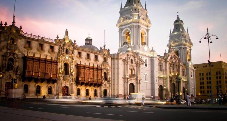 Plaza Mayor in Lima bij zonsondergang met mensen en auto's.