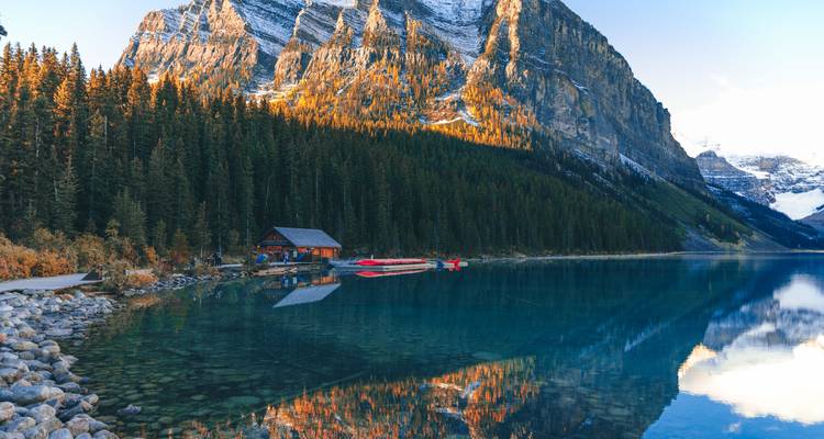 Lac avec un reflet de montagnes et une cabane en bois.