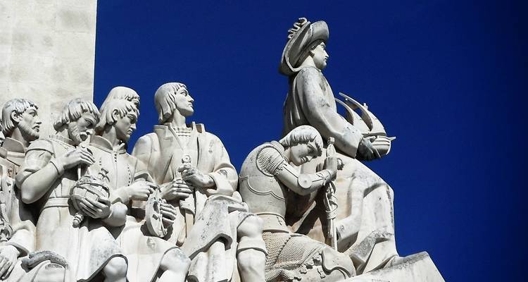 Un monumento con esculturas detalladas de figuras históricas contra un cielo azul despejado.