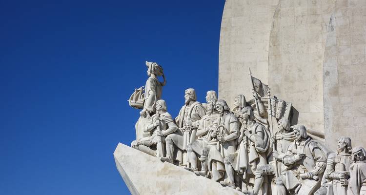 Un monumento con esculturas detalladas de figuras históricas contra un cielo azul despejado.