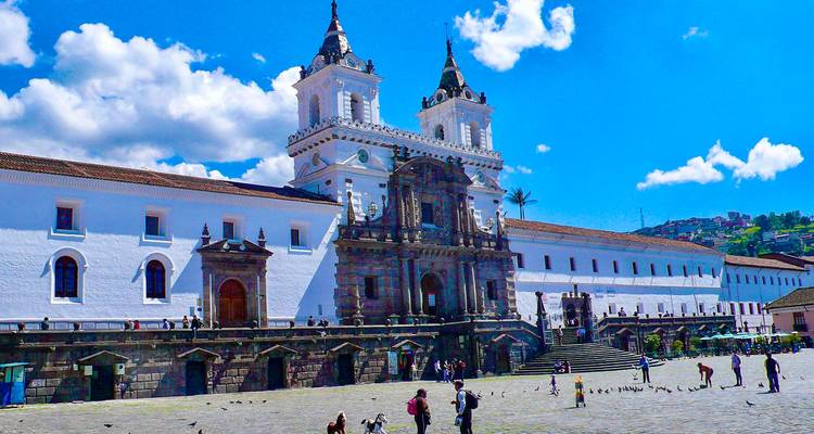 Een historische kerk met mensen op de binnenplaats onder een heldere hemel.