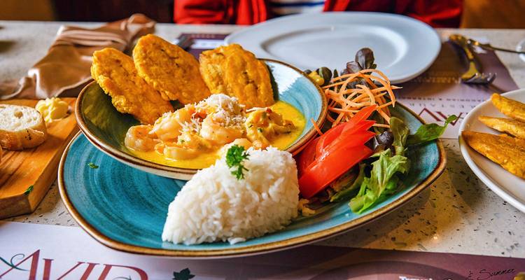 Angerichteter Teller mit Reis, Garnelen und gebratenen Kochbananen.