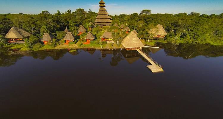 Vista aérea de un albergue con múltiples edificios de techo de paja en la selva.