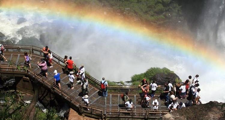 Vista aérea de turistas en un sendero en zigzag enmarcado por un arco iris brillante sobre la Garganta de Iguazú.