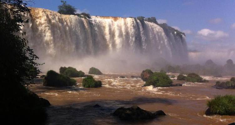 Machtvoller Wasservorhang der Iguazu-Wasserfälle, der in den nebligen, braunen Fluss darunter stürzt.