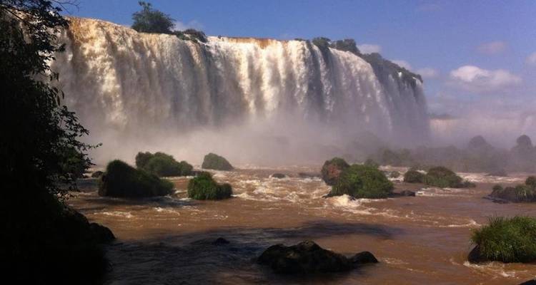 Los torrentes cargados de barro de las Cataratas del Iguazú se precipitan en un río marrón turbulento en un día soleado.