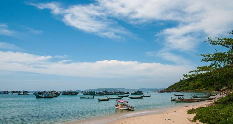 Fishing boats off a sandy beach with clear blue sky.