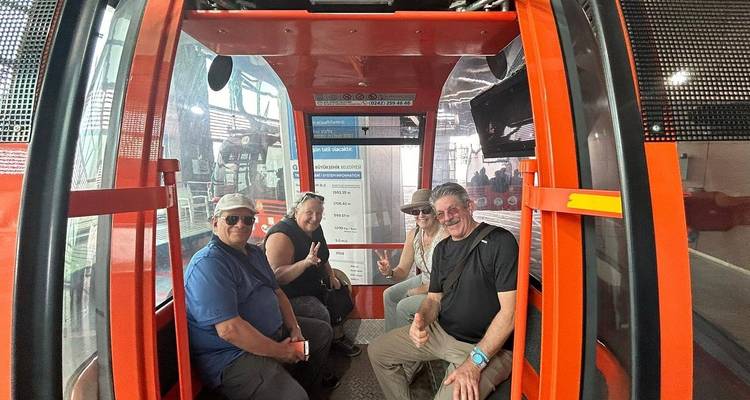 Quatre personnes dans un téléphérique, souriant et levant le pouce.